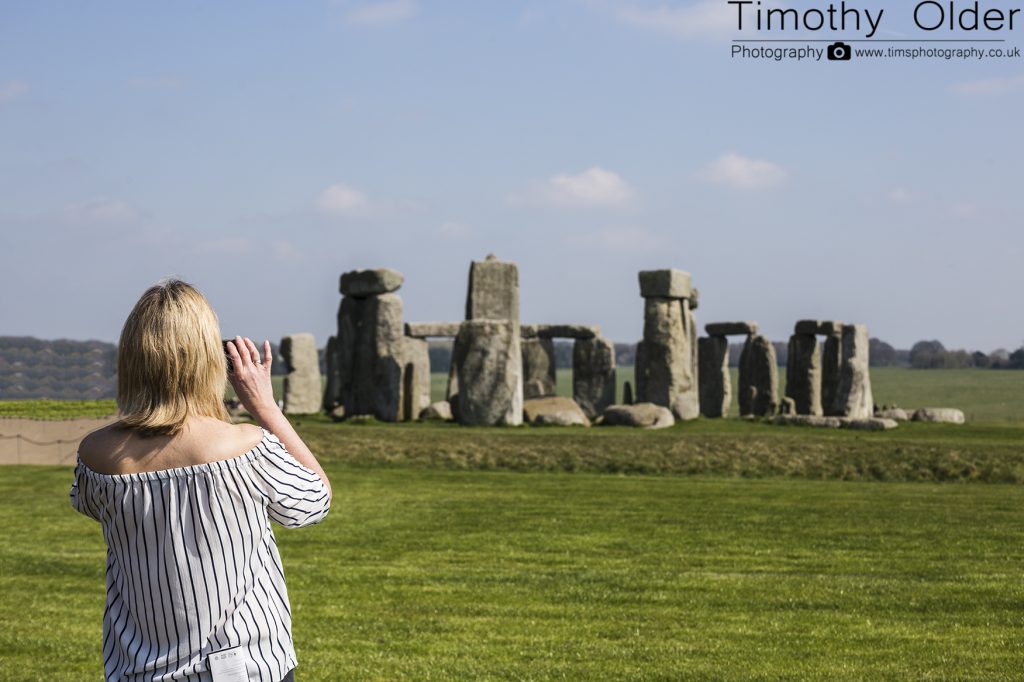 Stonehenge - A lady holding a smart phone - taking a picture of the stones